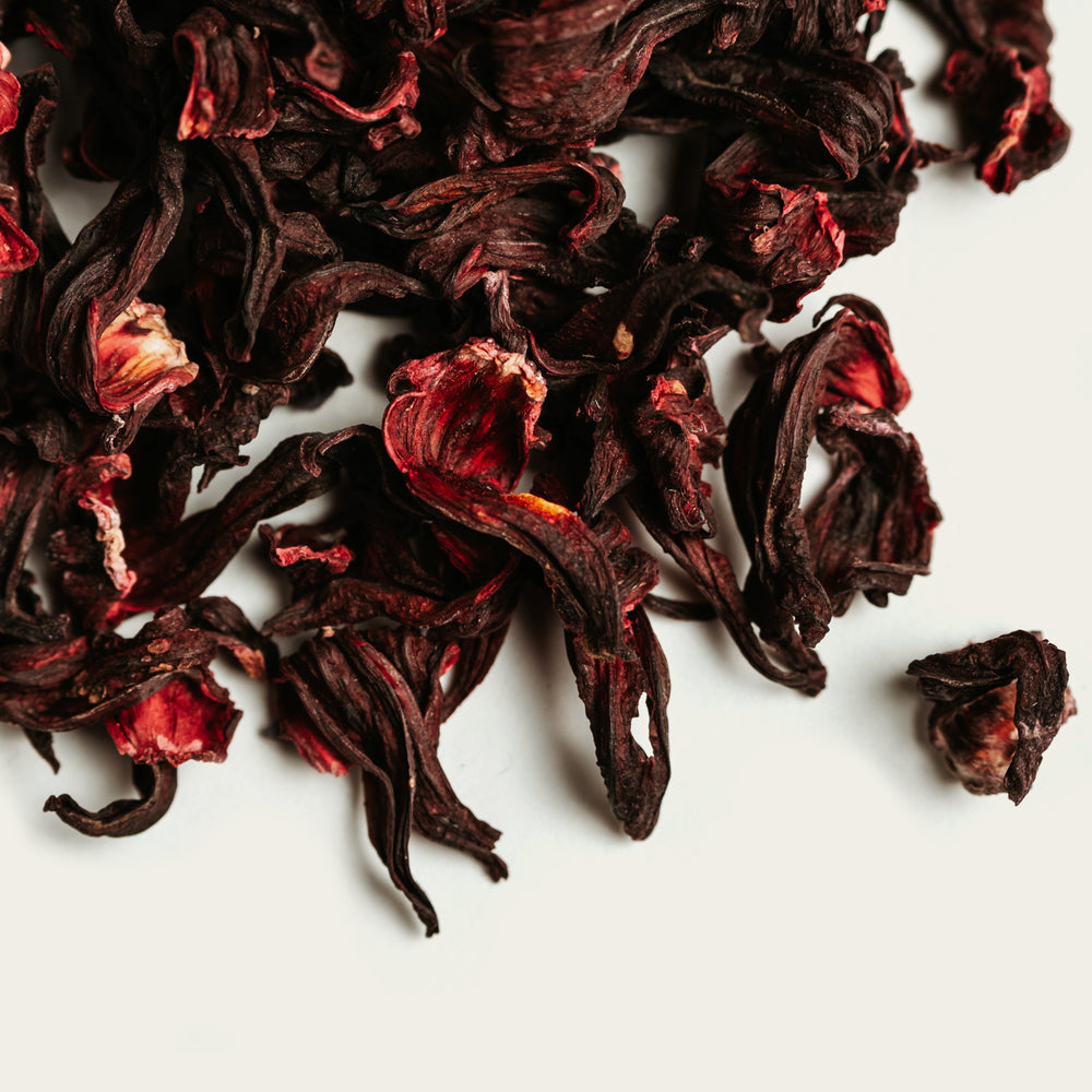 Dried dark red hibiscus tea leaves on a white background