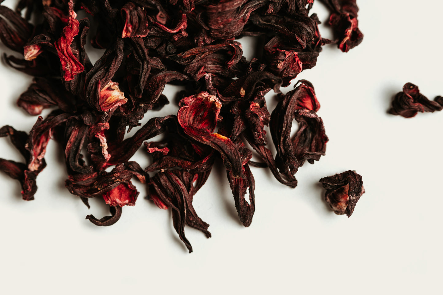 Dried dark red hibiscus tea leaves on a white background