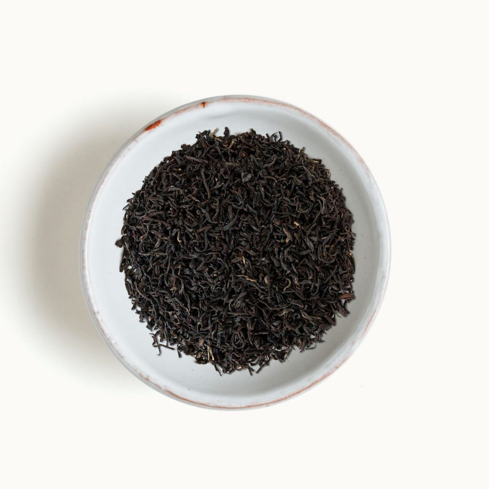 
                  
                    Assam black tea leaves in a white bowl on a light beige background
                  
                